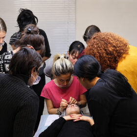 Πρακτική εκπαίδευση σε σεμινάριο Extra Volume Eyelash Extensions με συμμετέχουσες γύρω από μοντέλο εφαρμογής.